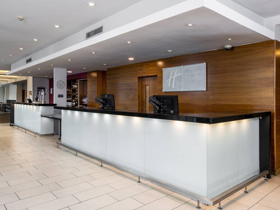 Et moderne receptionsområde med skranke, et ur og et skilt for Holiday Inn Express.