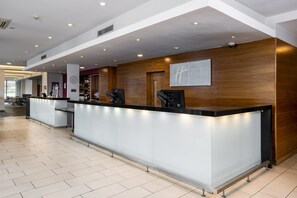 A reception area with a modern design, featuring a reception desk, a clock, and a sign for Holiday Inn Express.