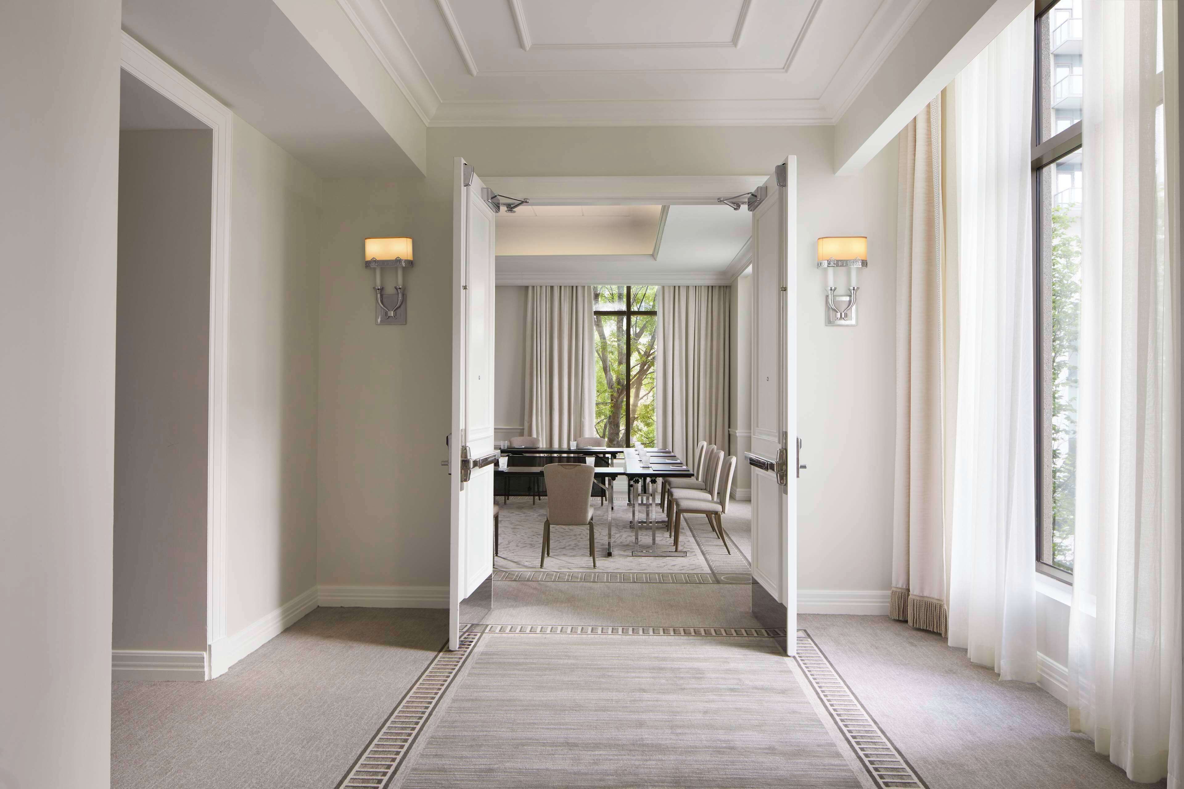 Un pasillo de hotel con comedor, luminarias y ventanas grandes.