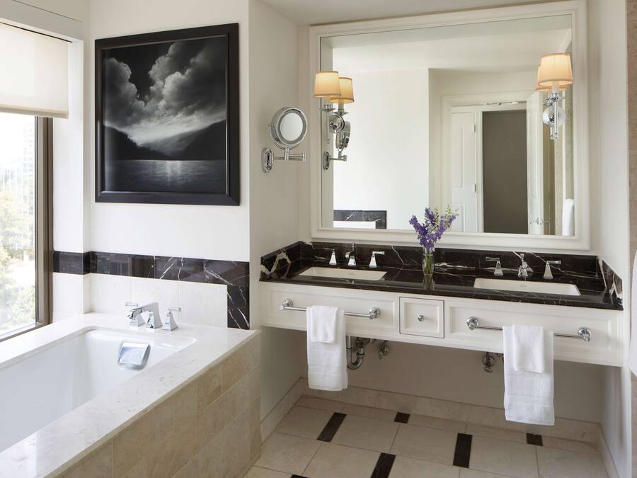 A modern bathroom with a large bathtub, a double sink vanity, and a large mirror.