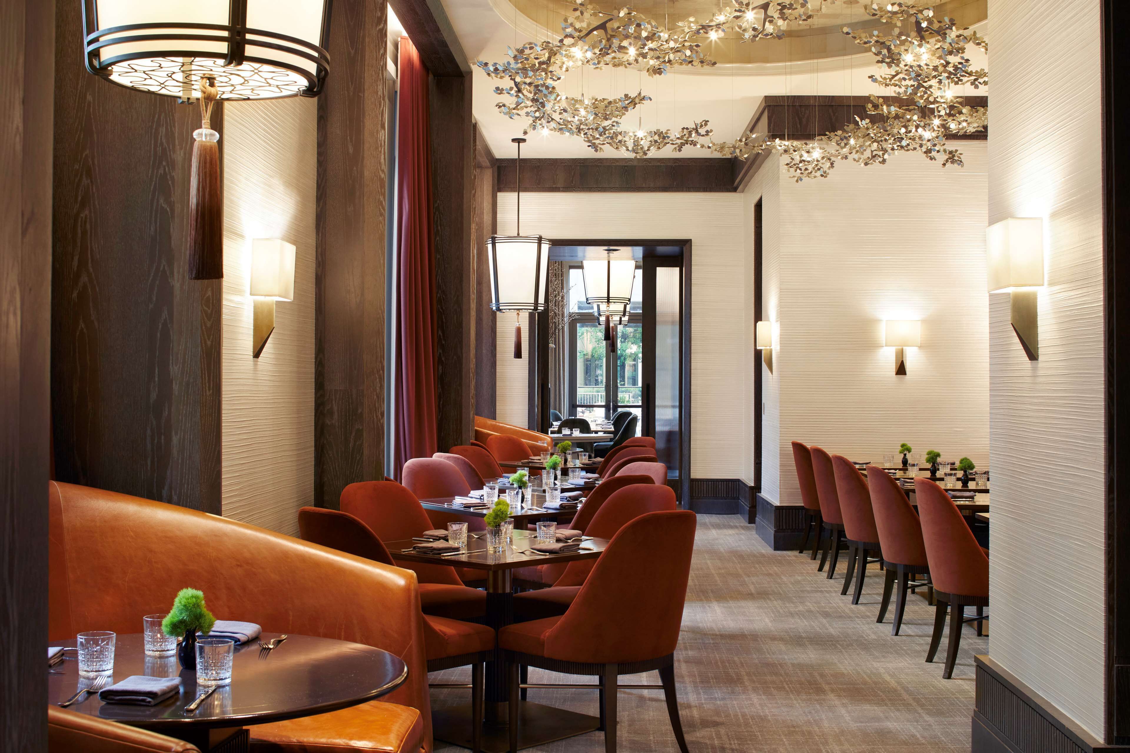 Un restaurant avec une longue table, de nombreuses chaises et des luminaires suspendus.