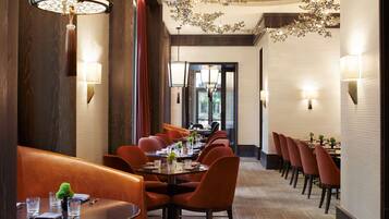 Un restaurant avec une longue table, de nombreuses chaises et des luminaires suspendus.