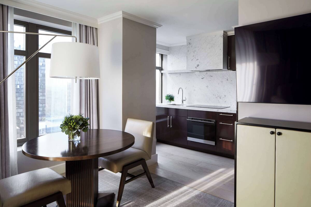 A modern kitchen with a built-in oven, a stainless steel refrigerator, and a window overlooking the city.