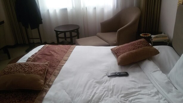 A hotel room with a bed, a chair, a small table, and a telephone. - Hanzhong Red Leaf Hotel (Hanzhong)