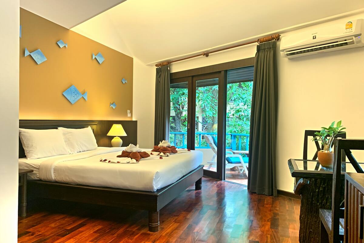 Habitación de hotel con una cama grande, vistas al exterior y una planta en maceta.
