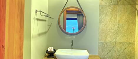 Ein Badezimmer mit einem Holzbadezimmer, einem weißen Waschbecken, einem runden Spiegel und einer Badewanne.
