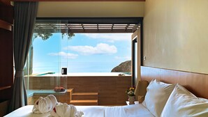 Una habitación de hotel con cama, vistas al océano y baño con ducha.