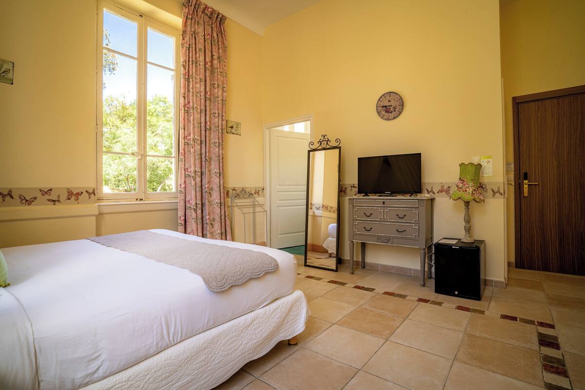 Une chambre à coucher avec un grand lit, une commode, un téléviseur et un miroir.