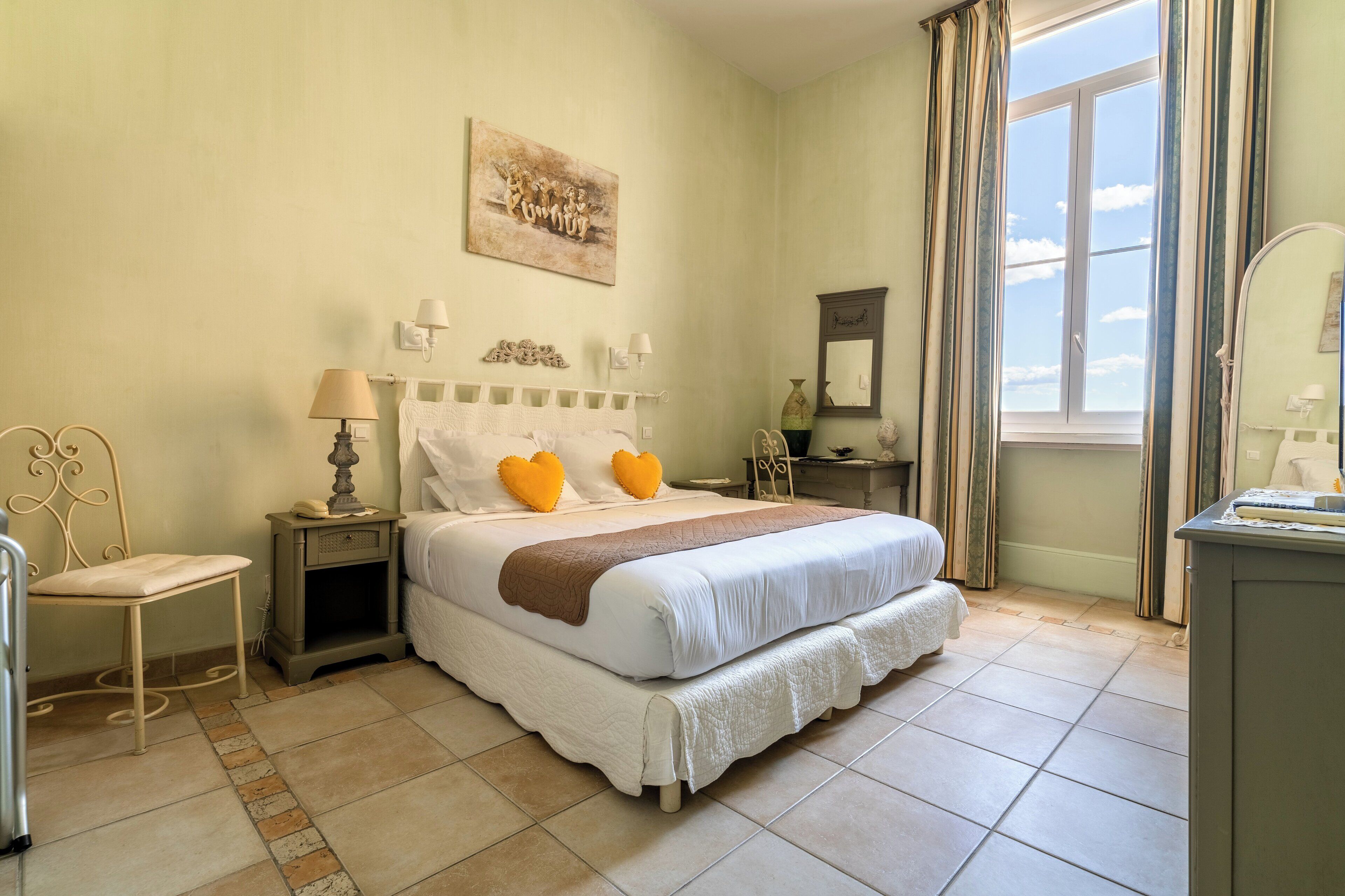 A neatly arranged bedroom with a bed, bedside tables, a chair, and a window with curtains.