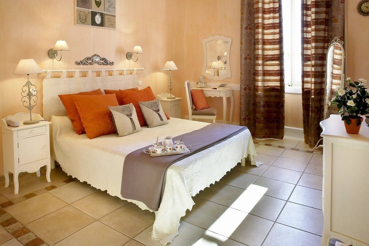 Une chambre à coucher comprenant un lit, des tables de chevet, une commode et un miroir.