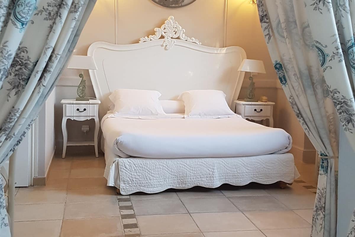 Une chambre à coucher comprenant un lit, deux tables de chevet, un élément décoratif fixé au mur et des rideaux.