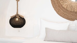 Un dormitorio con cama, almohadas blancas, un tapiz tejido y un espejo redondo.