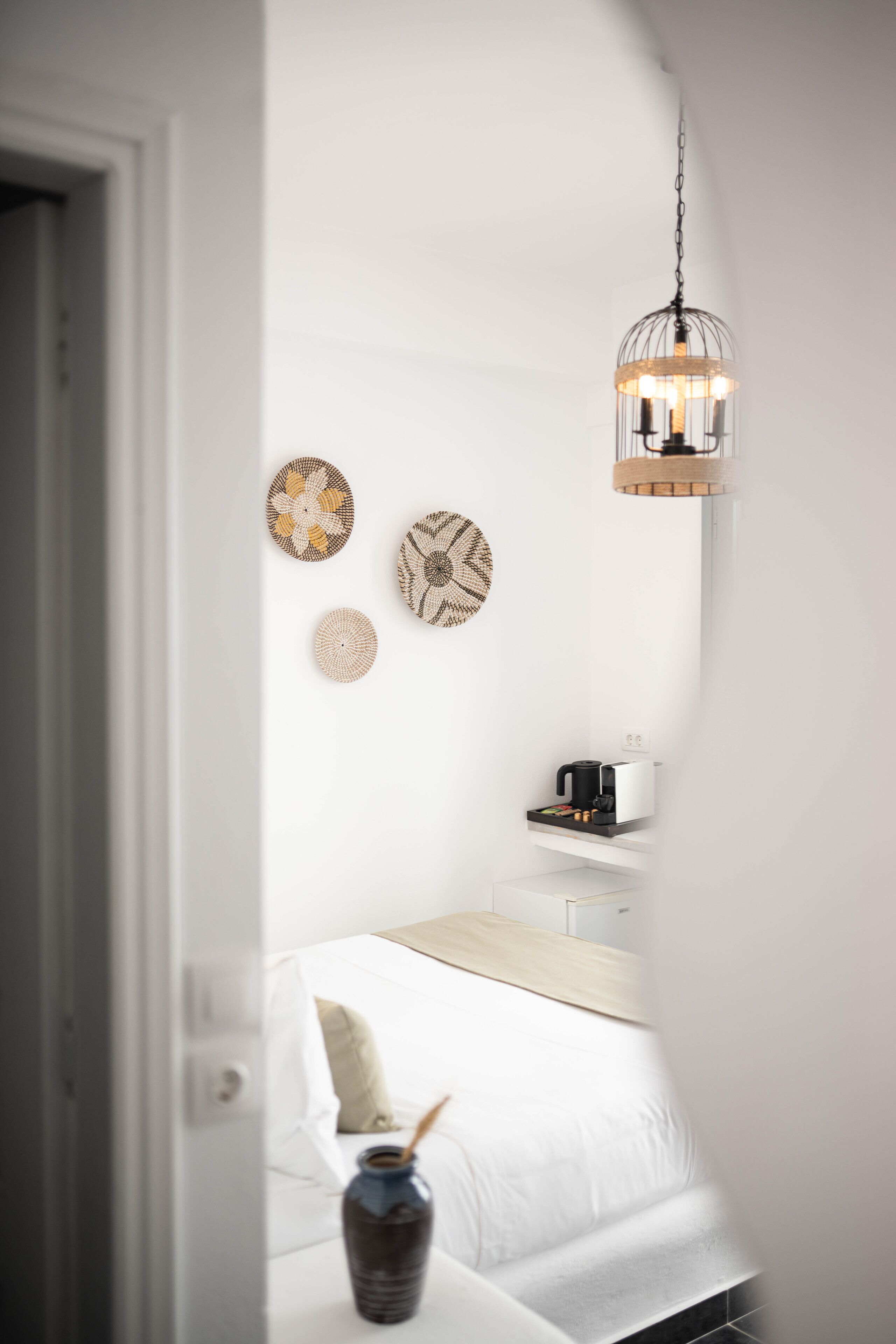 A bedroom with a bed, bedside table, and a hanging light fixture.