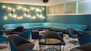 A modern lounge area with a teal-colored sofa, round tables, and blue chairs. - Metro Aspire Hotel, Sydney (Ultimo)