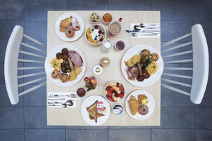 Une table de petit-déjeuner avec différents plats, couverts et une tasse de café.