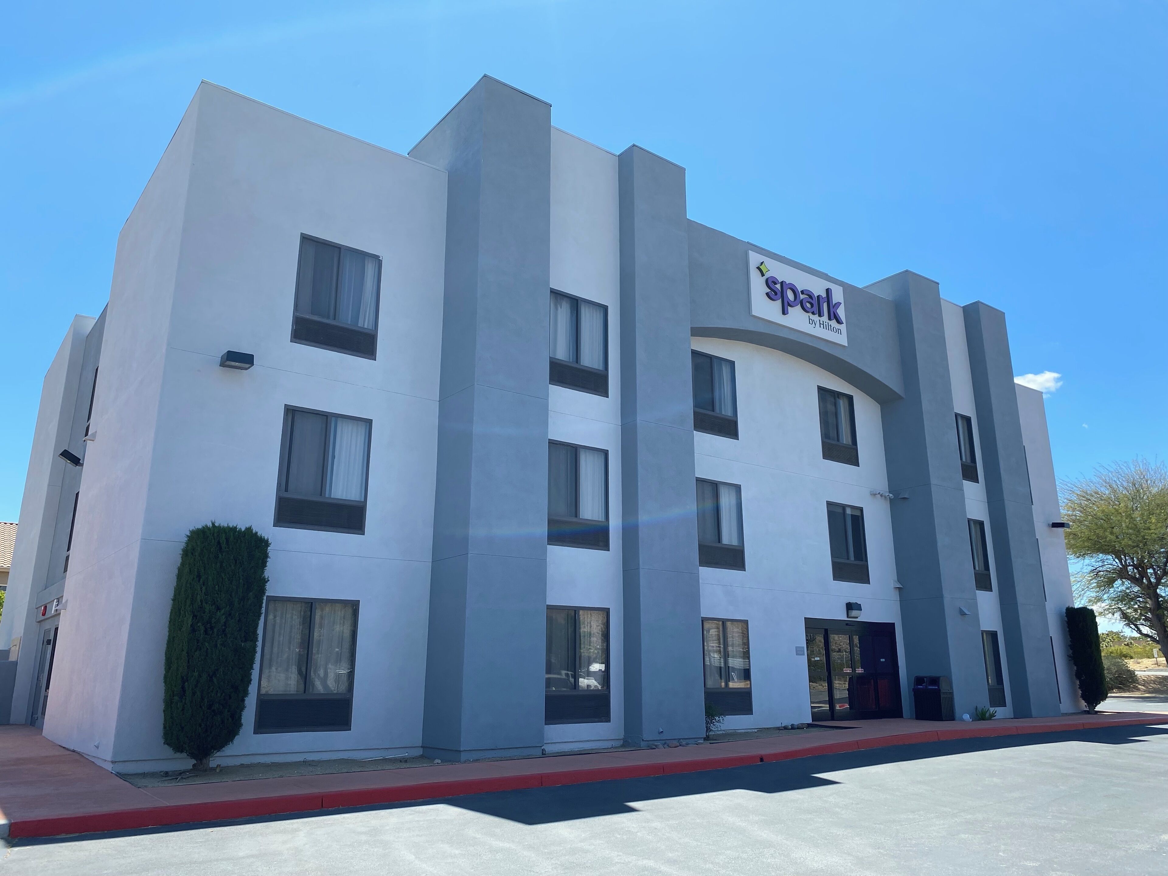 A modern hotel building with a sign reading "Spark by Hilton." It features a symmetrical facade with multiple windows and a central entrance.
