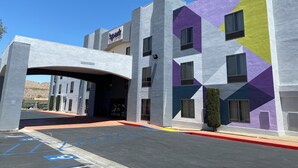 A hotel entrance with a modern design, featuring a geometric facade and a clear sky.