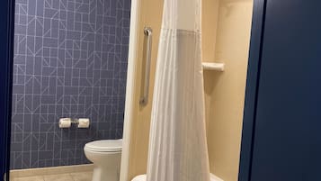 Un baño con ducha, inodoro y pared con diseño.