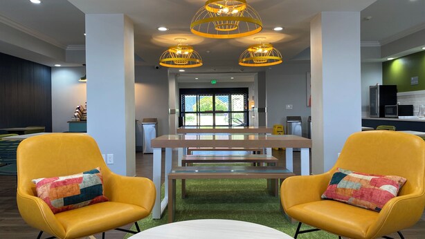 A modern interior with yellow chairs, a central table, and unique yellow ceiling lights.