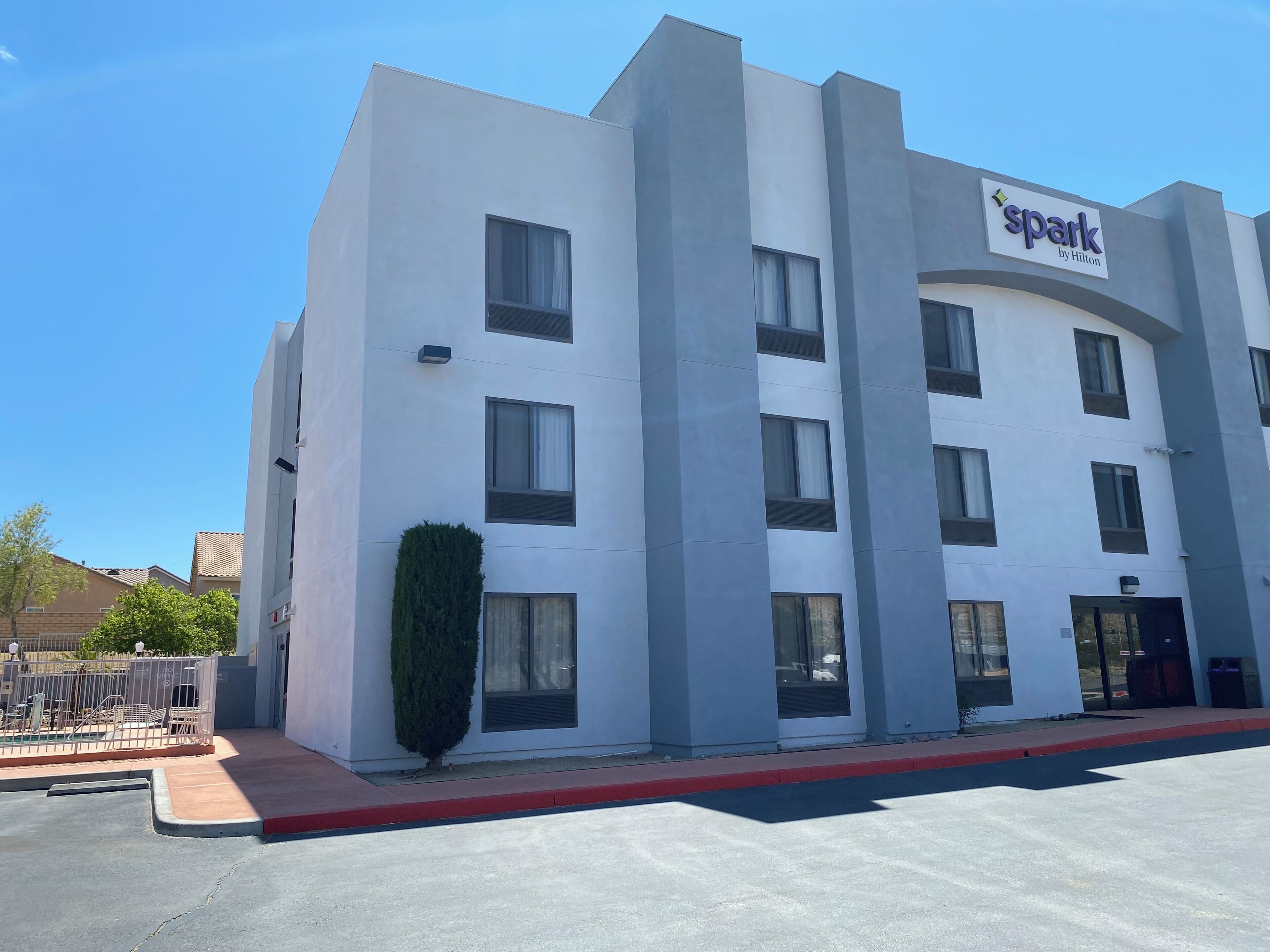 A modern hotel building with a flat facade, multiple windows, and a sign reading "spark by Hilton".