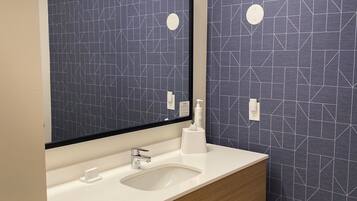 Un baño moderno con un lavamanos blanco, un espejo y una pared con un diseño geométrico.