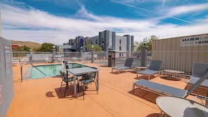 A pool area with lounge chairs and a table, surrounded by a fence.