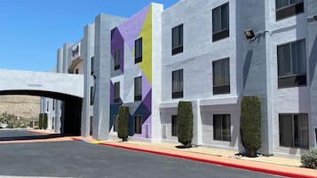 Un edificio moderno con fachada geométrica, múltiples ventanas y un estacionamiento.