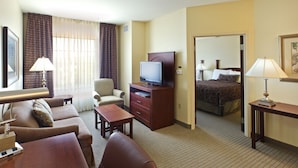 A hotel room with a bed, a television, a desk, a chair, and a lamp. - Staybridge Suites Hot Springs by IHG (Hot Springs)