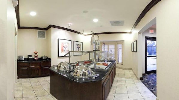 A buffet area with a central island, a refrigerator, and a window with blinds.