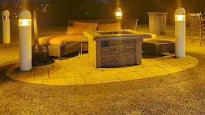 An outdoor seating area with a fire pit, cushioned seating, and four illuminated bollards. - Staybridge Suites Hot Springs by IHG (Hot Springs)