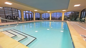An indoor swimming pool with clear water, a diving board, and a poolside area with chairs. - Staybridge Suites Hot Springs by IHG (Hot Springs)