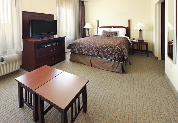 A hotel room with a bed, a television on a stand, a desk, and two bedside lamps.