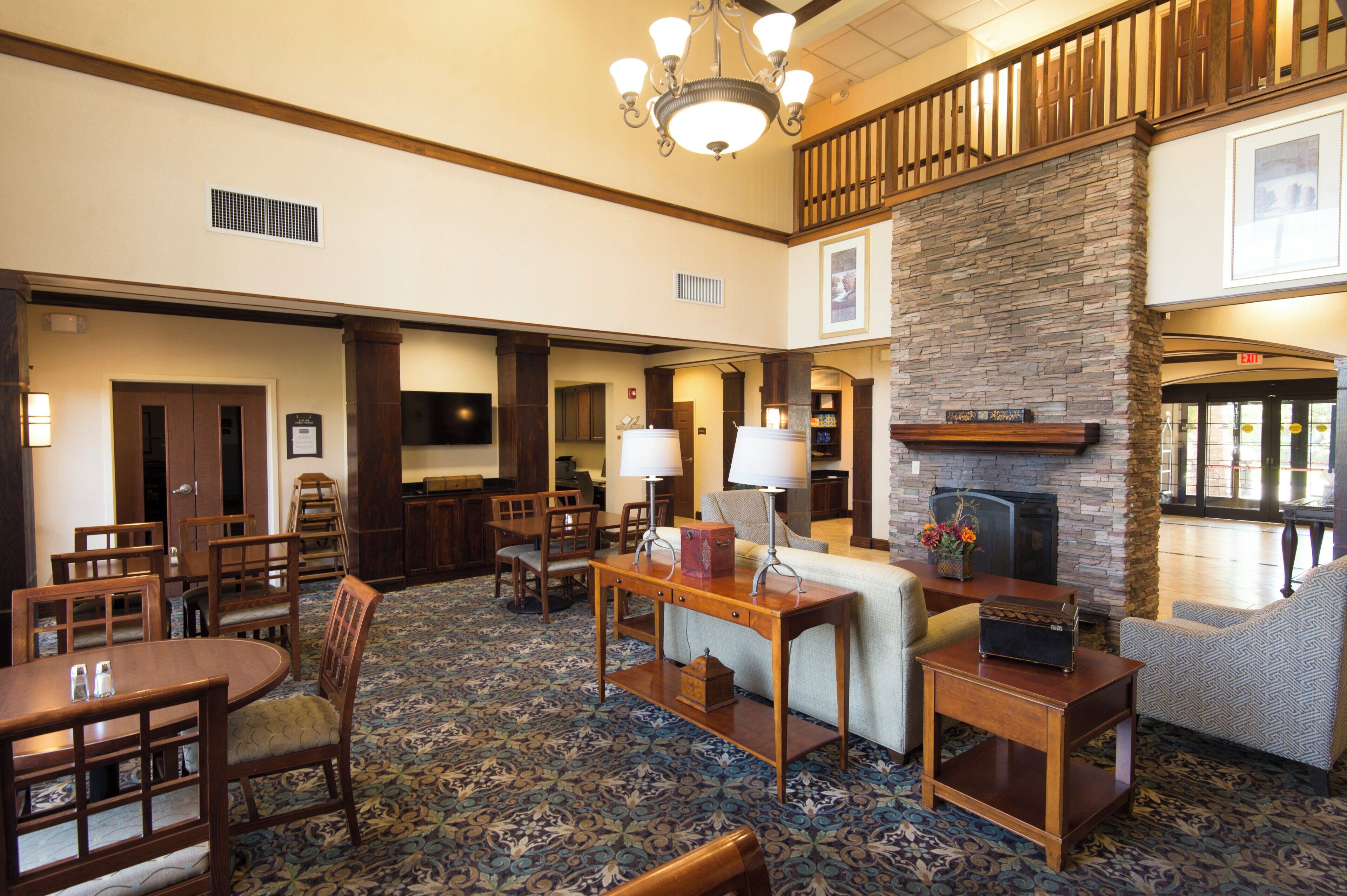 A hotel lobby with a fireplace, seating area, and a staircase.