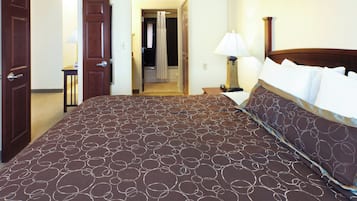 A hotel room with a large bed, a bedside table, a lamp, and a door leading to a bathroom.