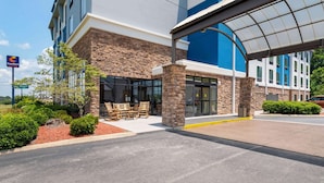 A hotel entrance with a stone facade, a covered walkway, and outdoor seating. - Comfort Suites Kodak Sevierville (Kodak)