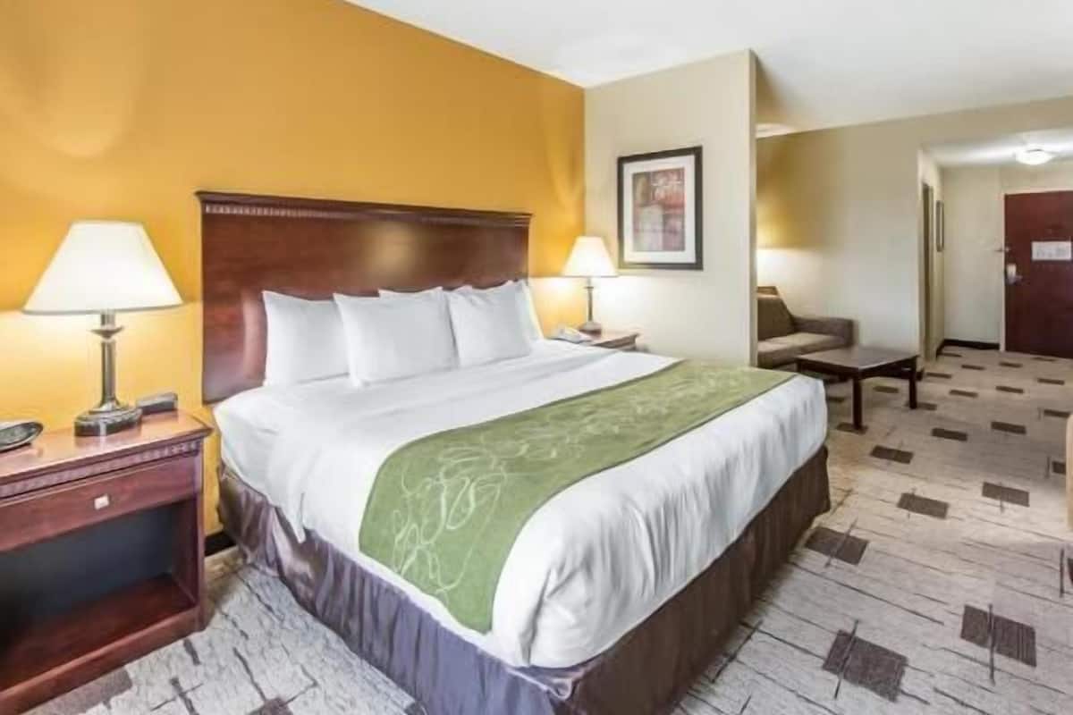A hotel room with a bed, bedside tables, a chair, and a door.
