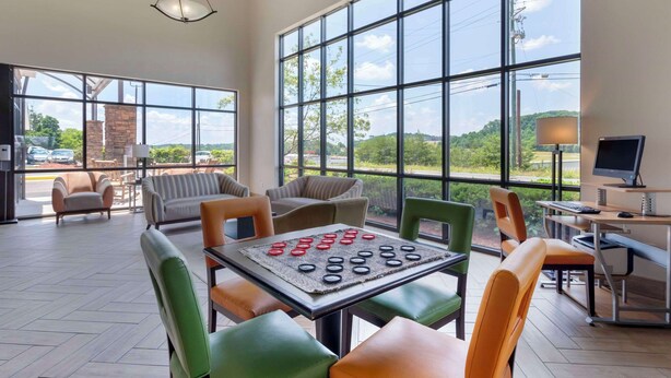 A spacious room with large windows, a table with a game, and a desk with a computer. - Comfort Suites Kodak Sevierville (Kodak)