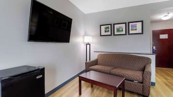 A living room with a flat-screen TV, a sofa, a coffee table, and framed pictures on the wall.