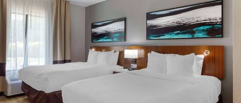 A hotel room with two beds, a large window with curtains, and two abstract paintings on the wall.