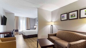 A hotel room with a bed, a sofa, a desk, a TV, and a lamp. - Comfort Suites Kodak Sevierville (Kodak)