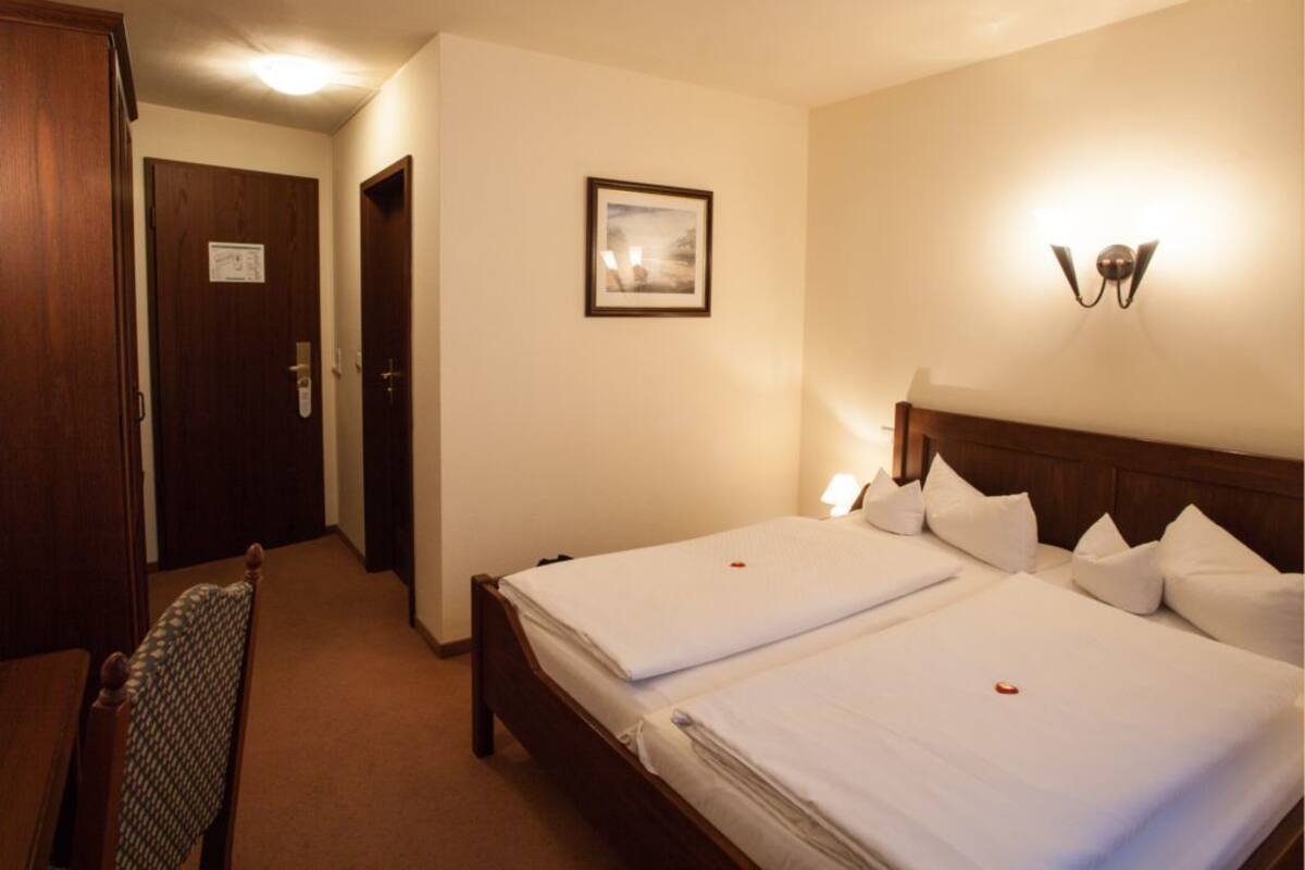 Habitación de hotel con dos camas, cabecero de madera, un cuadro en la pared y una puerta con un letrero.
