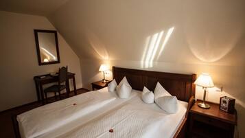 Ein Hotelzimmer mit einem großen Bett, zwei Nachttischen mit Lampen, einem Sessel und einem Spiegel an der Wand.
