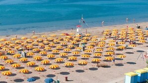 A beach with numerous sun umbrellas arranged in rows. - Hotel Merano (Grado)