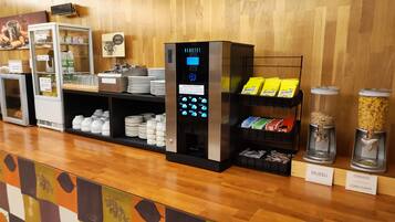 Een zelfbedieningskiosk met een digitaal scherm, een gekoeld display en een plank met verpakte snacks.