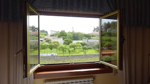 Una habitación con ventana que da a un jardín y un edificio.