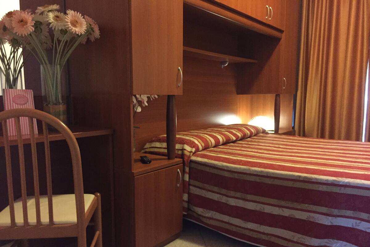 Habitación pequeña con una cama doble, un escritorio y una silla.
