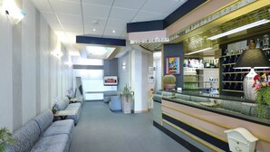Vestíbulo de hotel con zona de bar, asientos y mostrador de recepción.