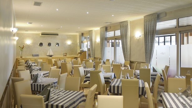 Un restaurante con manteles a rayas, sillas color beige y una decoración de pared con temática náutica.