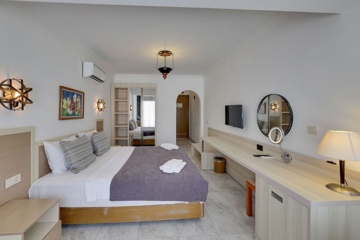 Une chambre à coucher moderne avec un lit, une table de chevet et une coiffeuse dotée d’un miroir et d’une lampe.