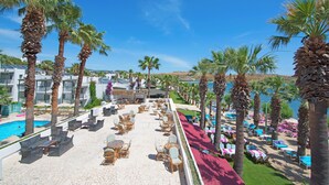 A resort with a pool, lounge chairs, and palm trees. - Sami Beach Hotel (Bodrum)